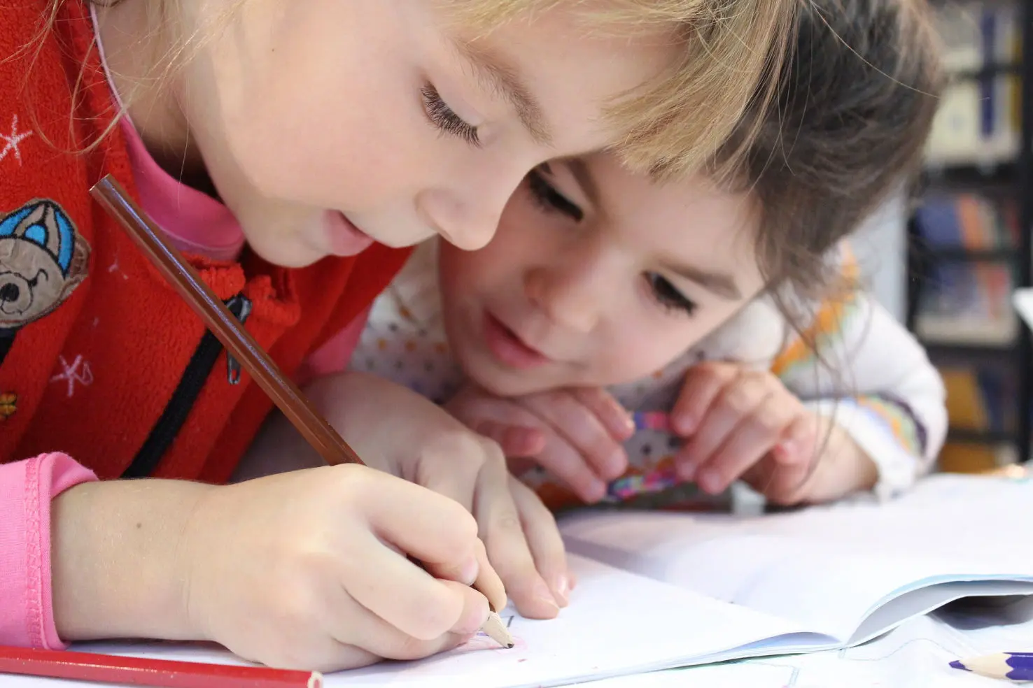 Two homeschoolers drawing in a book